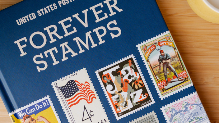 A book with U.S. postage stamps on the cover sitting on a wooden table