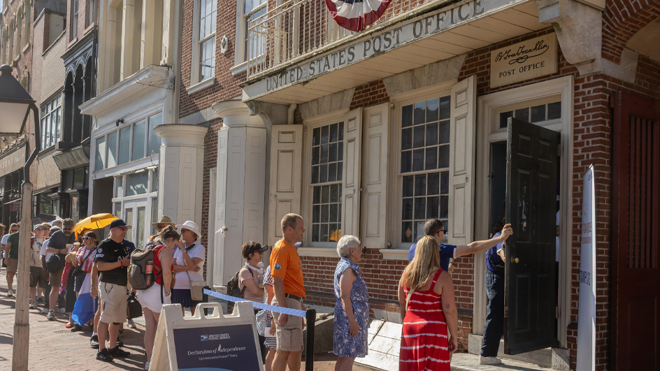 Men and women in a line outside a historical brick-faced building