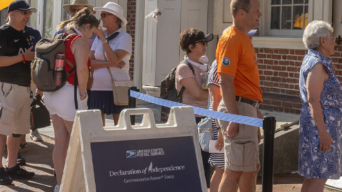 Men and women in a line outside a historical brick-faced building