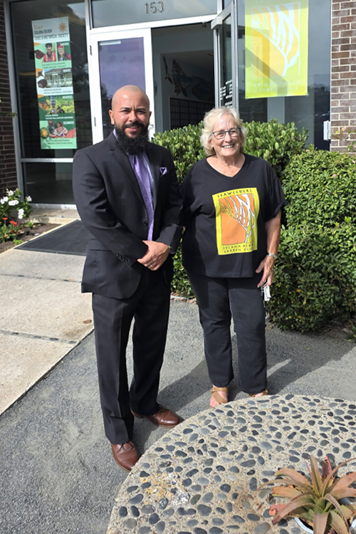 A man and woman wearing dark clothing standing in a garden outside of a Post Office