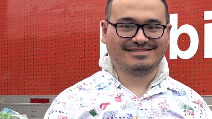 Man in a patterned shirt standing in front of a red mobile kitchen trailer