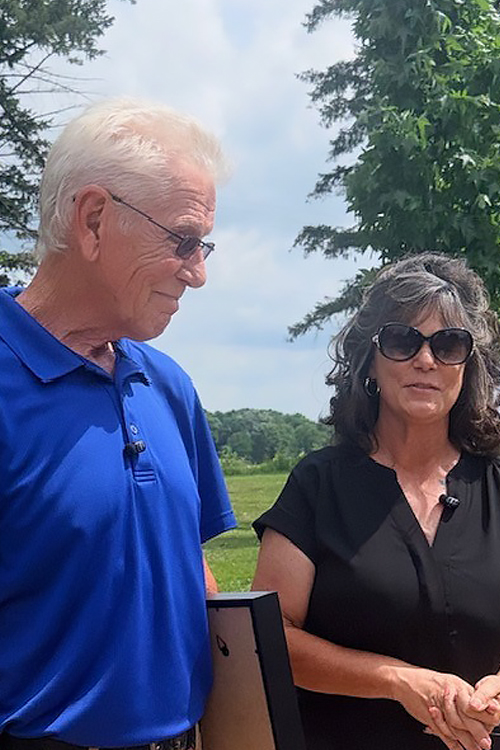 Man in a blue shirt standing next to a woman in a black shirt outdoors