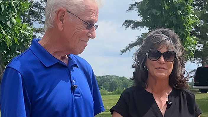 Man in a blue shirt standing next to a woman in a black shirt outdoors