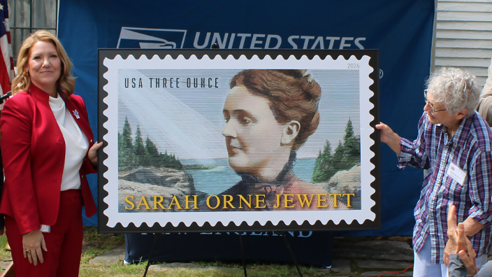 Groups of people standing on both sides of an enlarged image of the Sarah Orne Jewett stamp