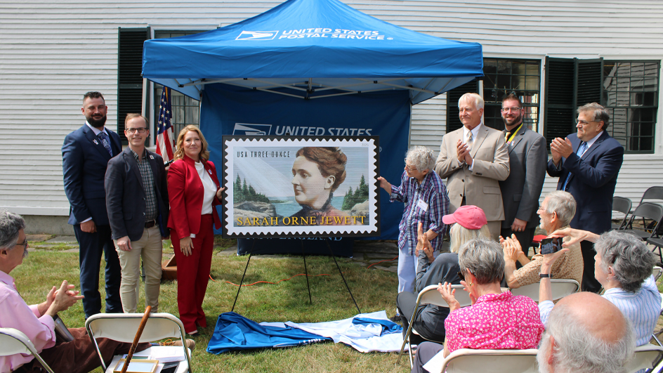Groups of people standing on both sides of an enlarged image of the Sarah Orne Jewett stamp