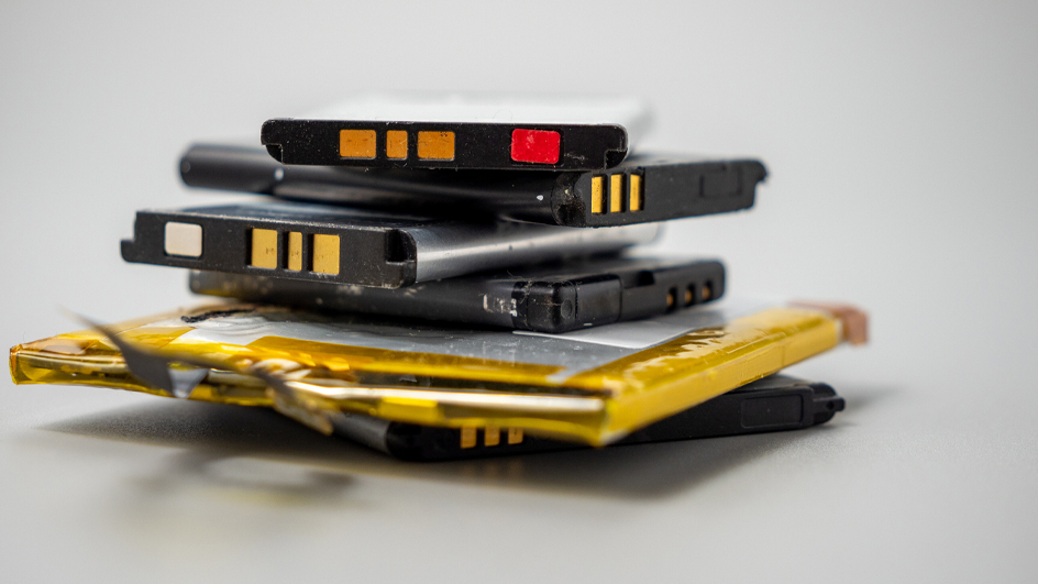 Stack of old cell phone batteries on a gray background