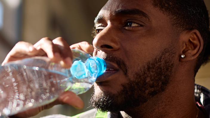 Man wearing a safety vest and drinking from a bottle of water