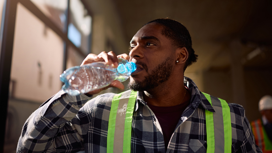Man wearing a safety vest and drinking from a bottle of water
