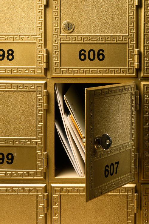 Close-up of open numbered Post Office box showing mail inside.