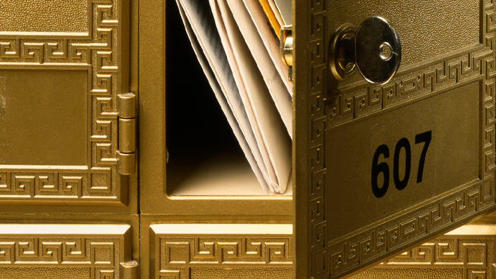 Close-up of open numbered Post Office box showing mail inside.