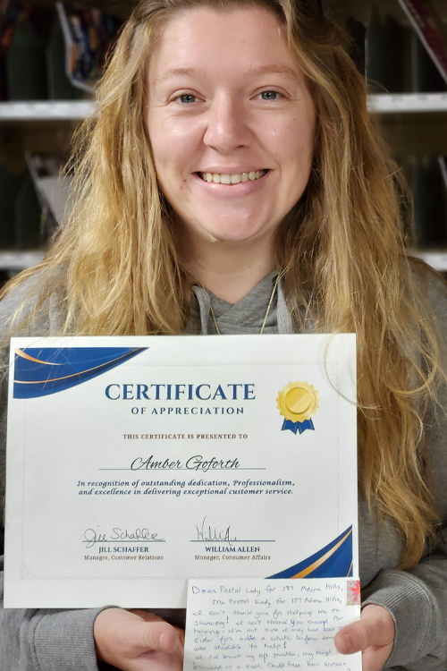 A woman holding a certificate of appreciation and a handwritten note