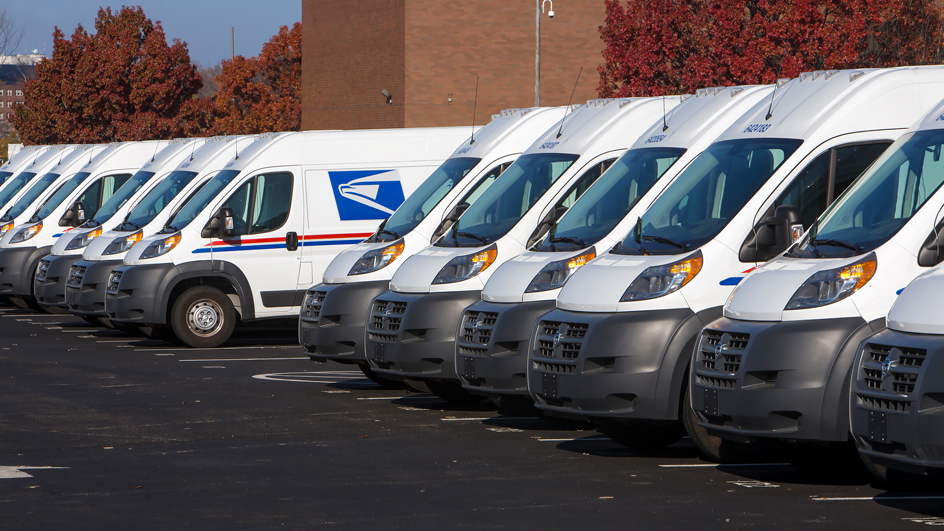 A row of USPS delivery vans in a parking lot