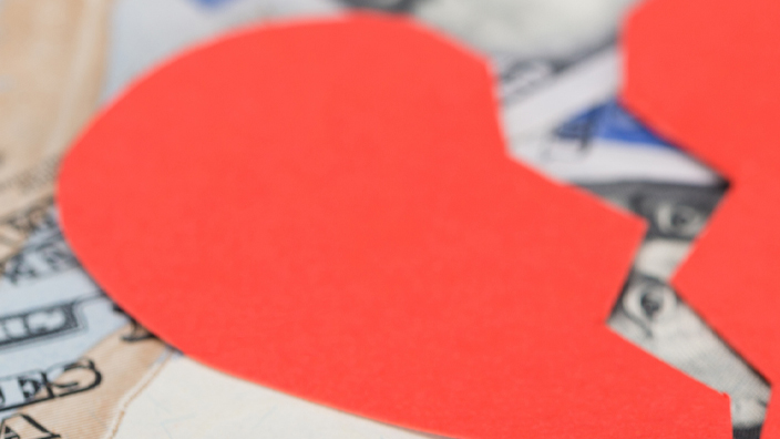 Red heart broken in half sitting on $100 bills