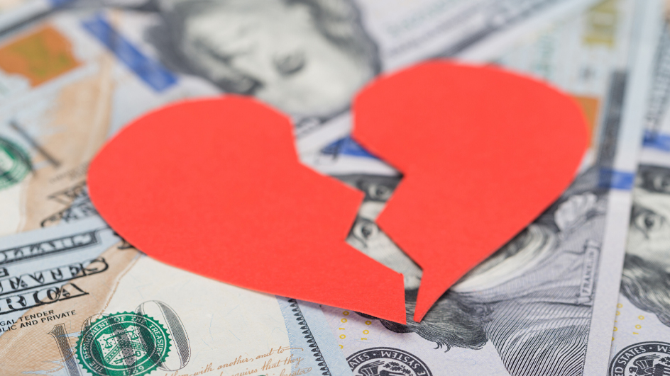 Red heart broken in half sitting on $100 bills
