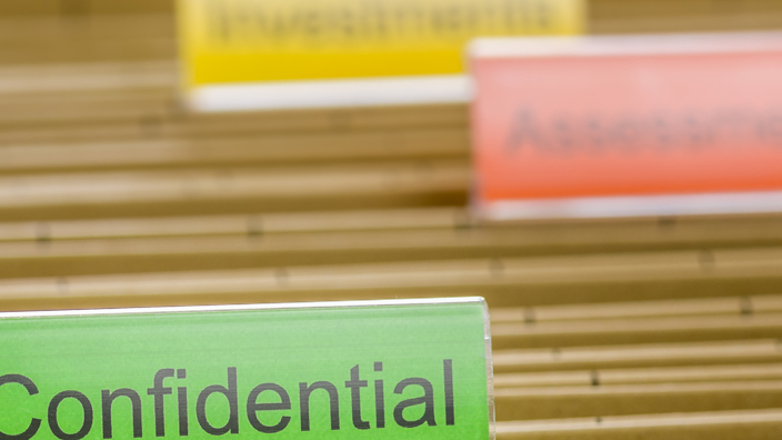 Brown hanging file folder with a green tab labeled “confidential”