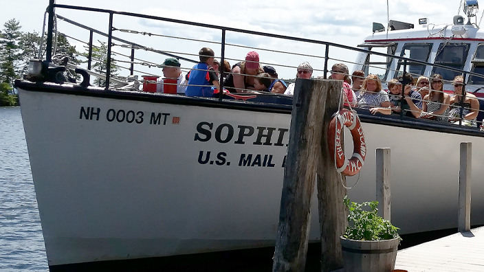 A boat with passengers is docked at a wooden pier