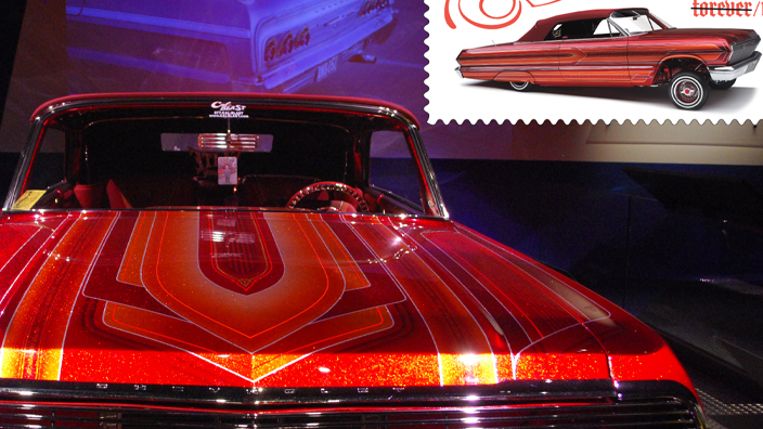 A red 1963 Chevrolet Impala in a dark room with a spotlight shining on it