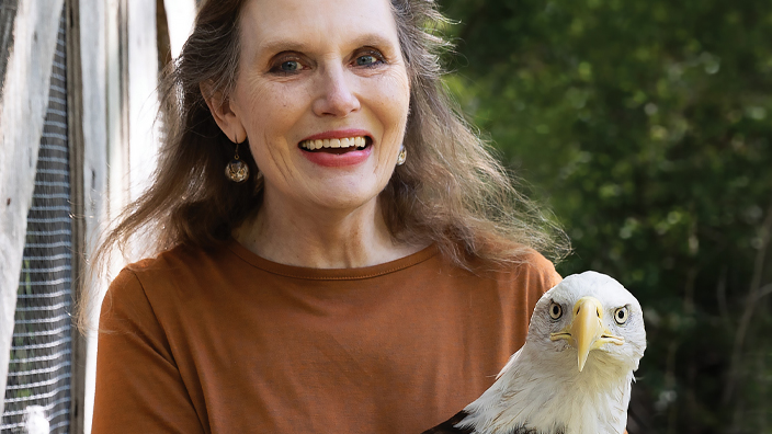 Woman standing outdoors and holding an eagle