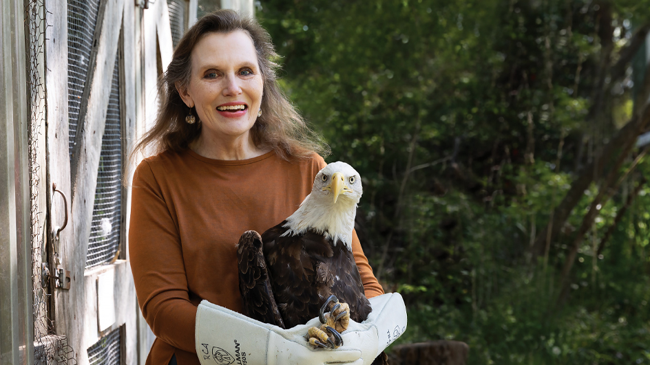 Woman standing outdoors and holding an eagle