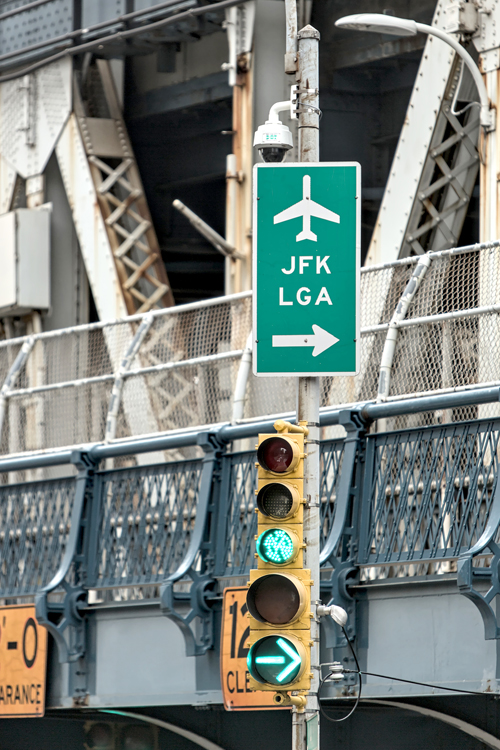 A green sign on a traffic light with Manhattan Bridge in the background