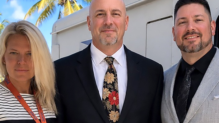 Three people in professional business attire standing side-by-side outdoors