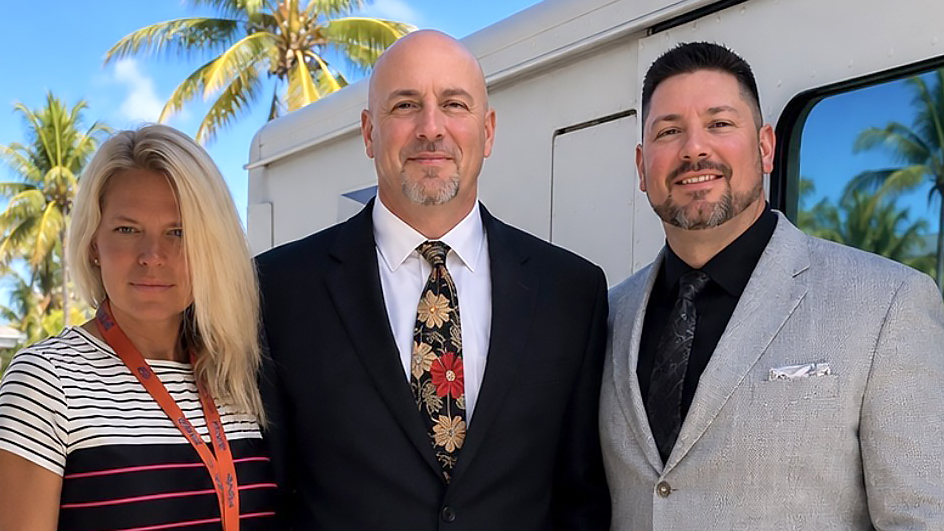 Three people in professional business attire standing side-by-side outdoors
