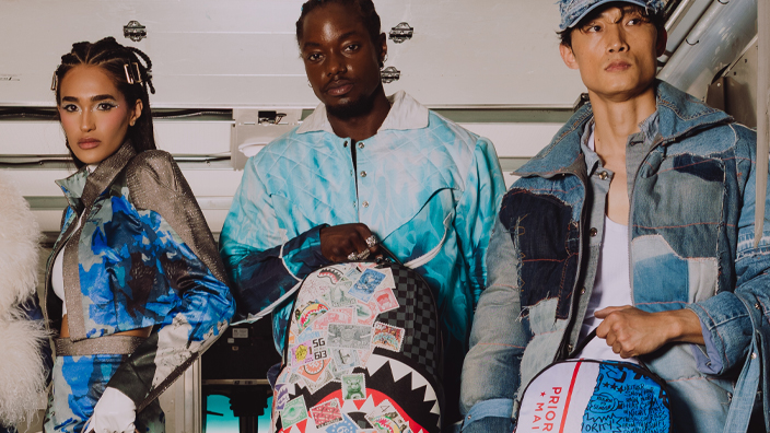 Five people standing in the back of a delivery vehicle display colorful Postal Service-themed bags and backpacks