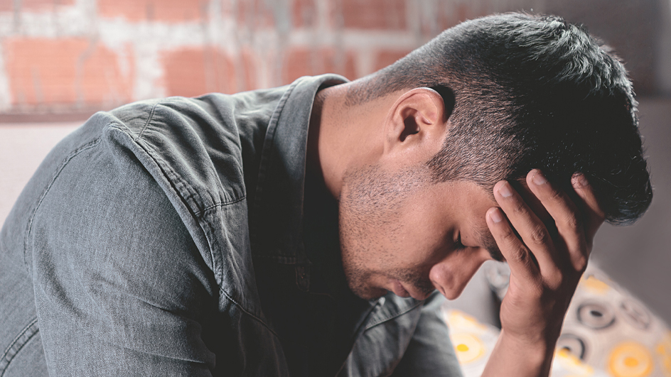 Young man sitting with his head hanging down