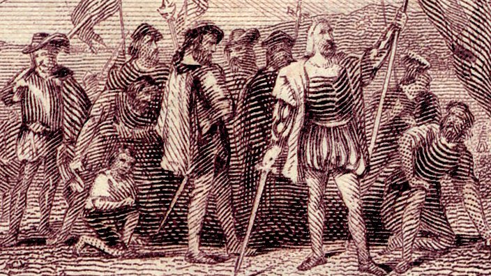 A USPS postage stamp depicting Christopher Columbus and members of his crew arriving on land after their 1492 voyage