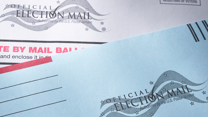 Two Election Mail envelopes laying on top of an American flag