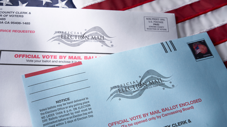 Two Election Mail envelopes laying on top of an American flag