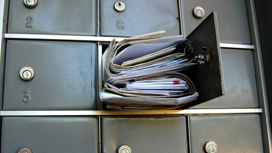 Partial view of a cluster box unit with one box open and overflowing with mail