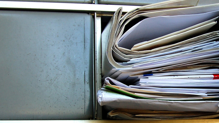 Partial view of a cluster box unit with one box open and overflowing with mail