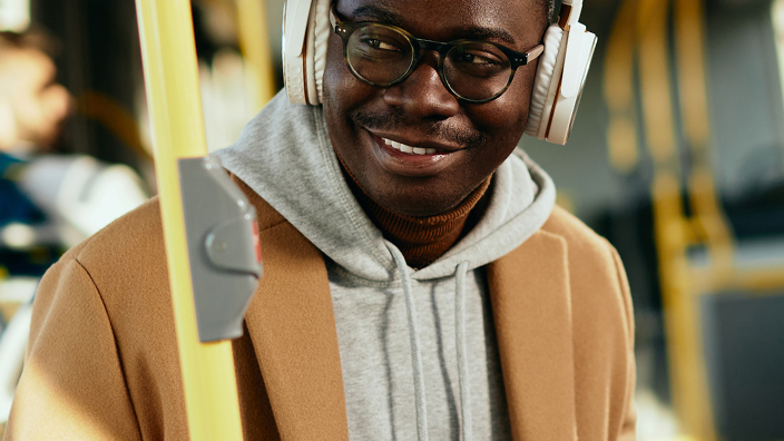 Young man on a bus wearing headphones and using his cellphone