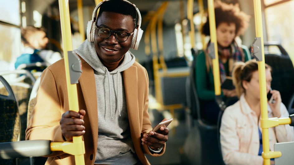 Young man on a bus wearing headphones and using his cellphone
