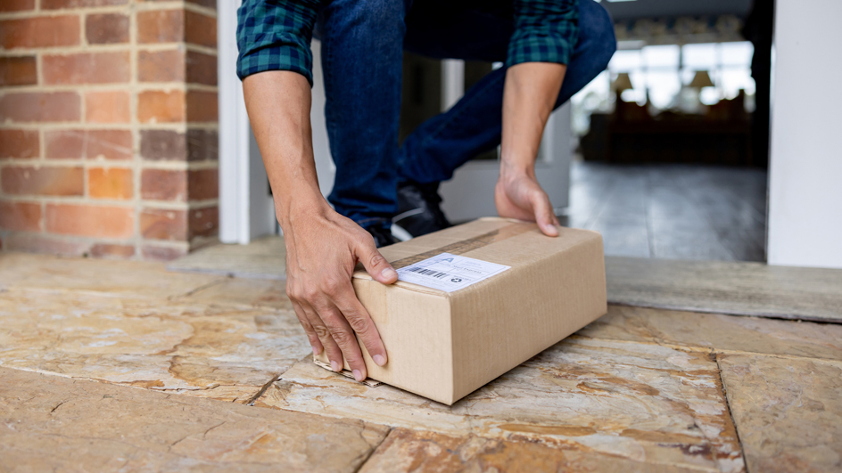Close-up on a man picking up a package left on the porch of his house
