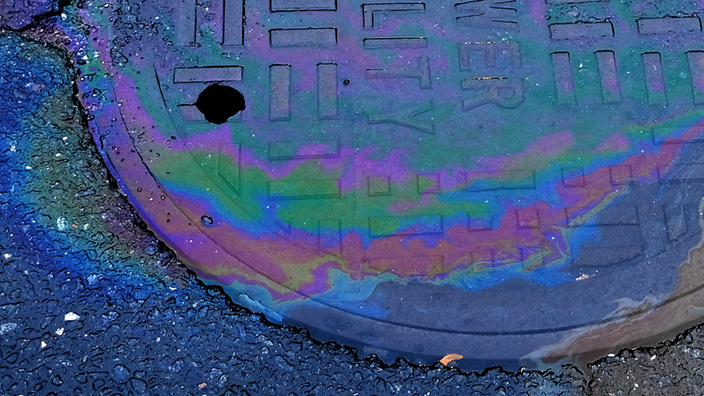 Oil-tainted water draining into a sewer utility cover