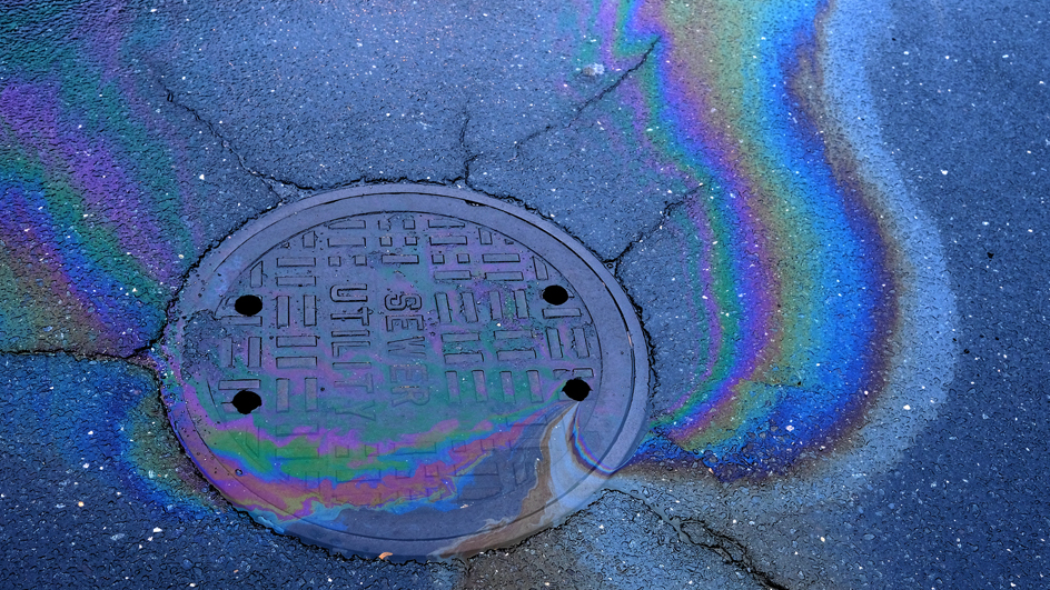 Oil-tainted water draining into a sewer utility cover