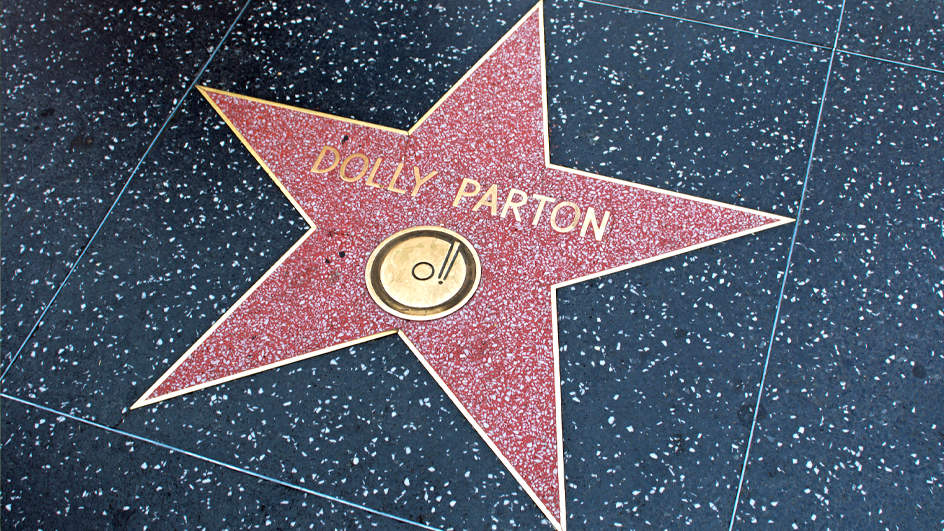 Image of a red star on a sidewalk with the name “Dolly Parton” and a music record icon inside of it