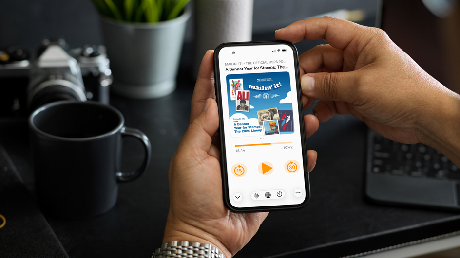 A pair of hands holding a cellphone displaying an episode of “Mailin’ It!”, the USPS podcast
