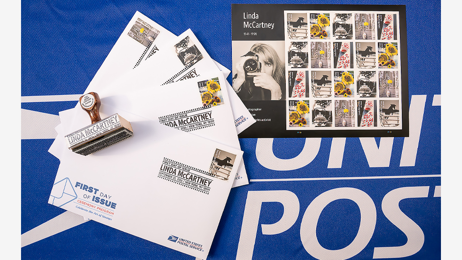 A sheet of stamps and four first-day-of-issue envelopes sitting on a table covered in a blue table cloth